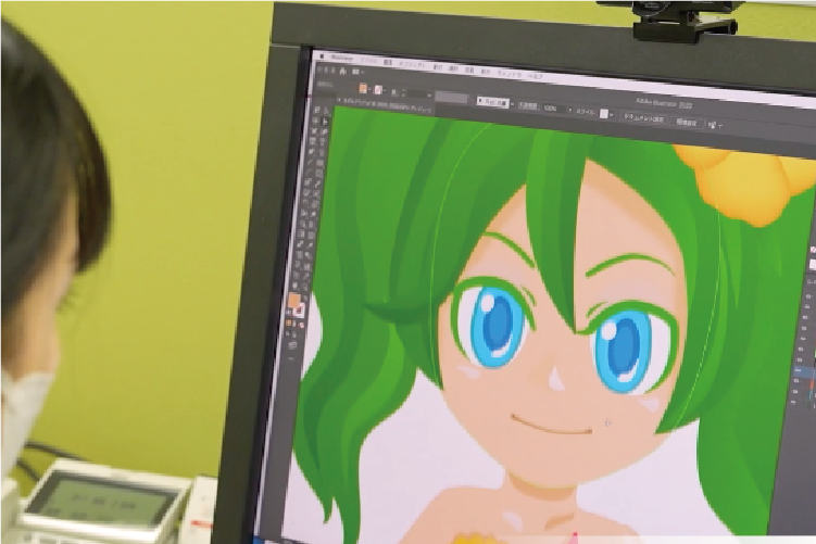 パソコンでバーチャルキャラクターのデザインを行う社員